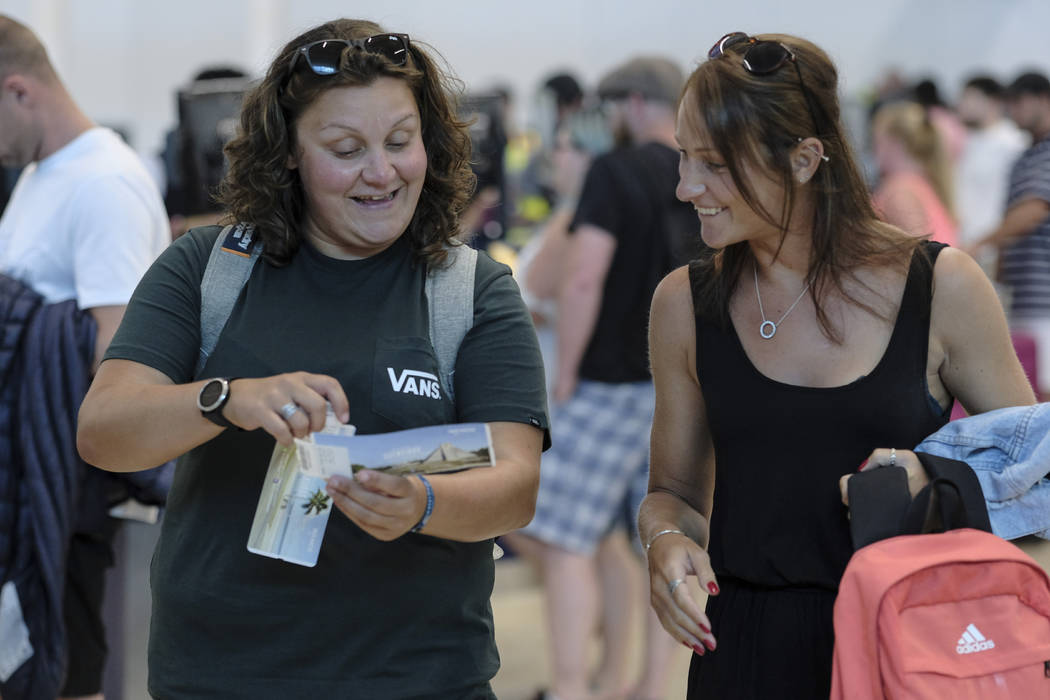 Tourists smile after checking in an alternate flight, at the Cancun airport in Mexico, Monday, ...