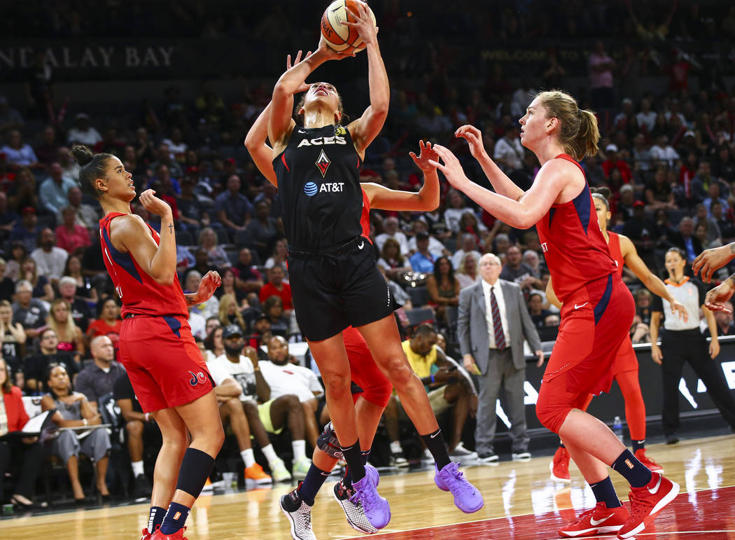 Las Vegas Aces' forward Dearica Hamby, center, looks to shoot under pressure from Washington My ...