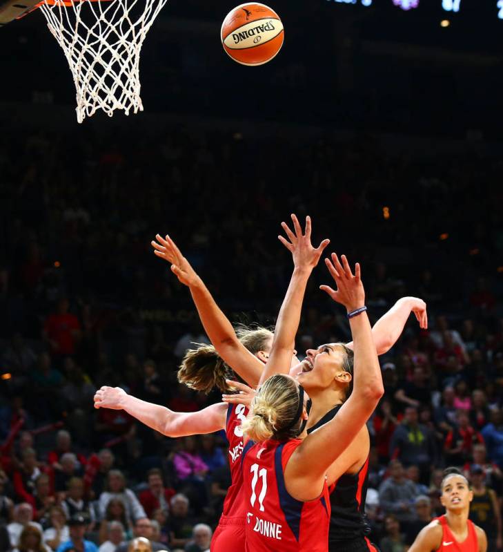 Las Vegas Aces' Liz Cambage, right, shoots between Washington Mystics' Elena Delle Donne (11) a ...