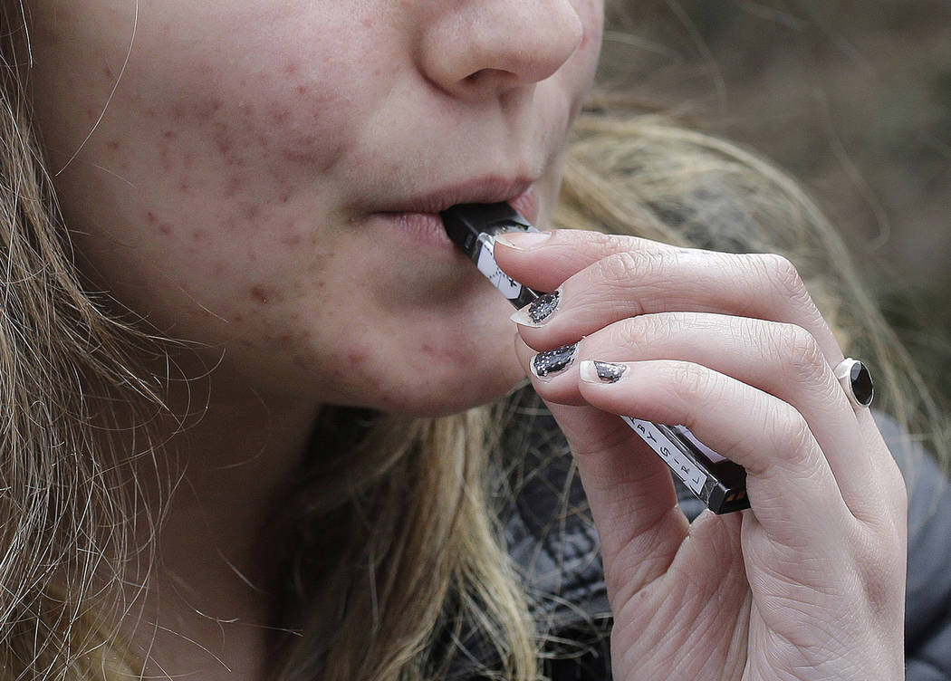 FILE - In this April 11, 2018 file photo, a high school student uses a vaping device near a sch ...