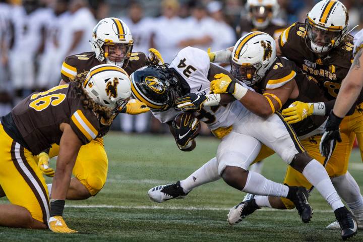 Wyoming defenders Cassh Maulia (46), Logan Wilson (30)and Mario Mora (97) tackle Missouri runni ...