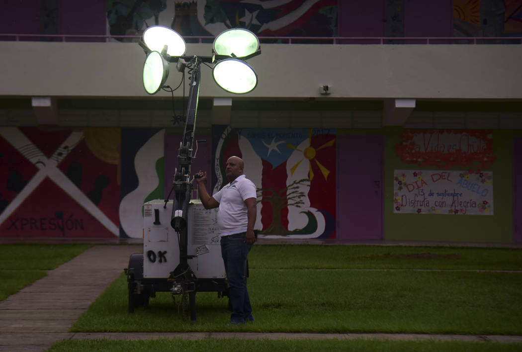 A municipal worker turns on portable lights atthe inner courtyard of Ramon Quinones Medina High ...