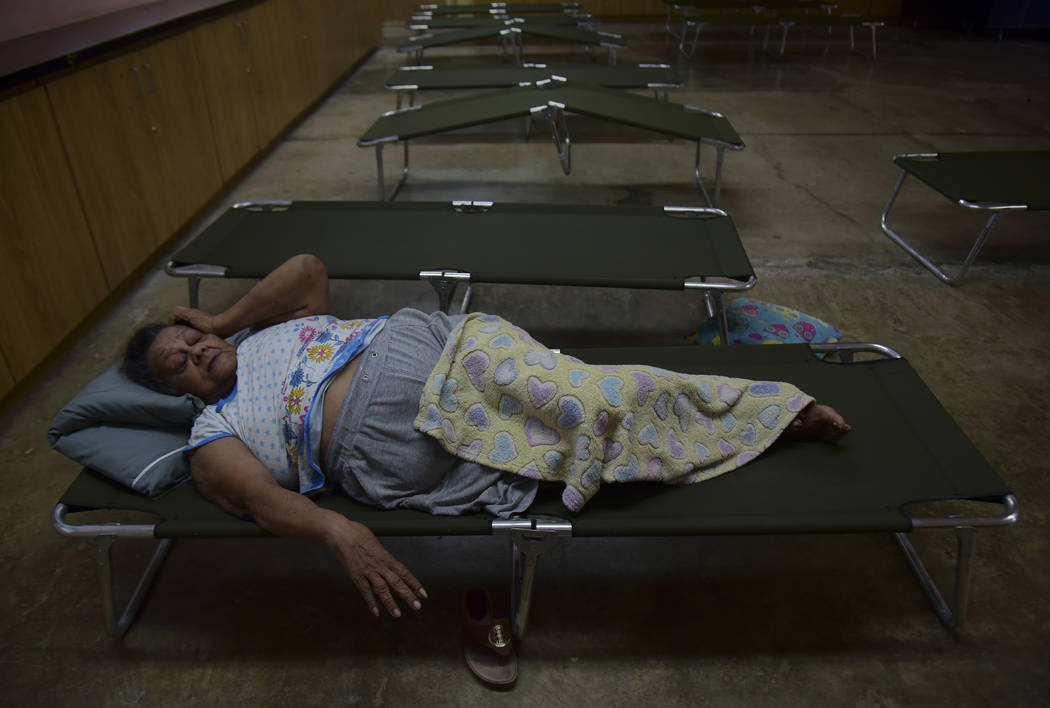 Luz Aponte Velazquez lies on a cot at the Ramon Quinones Medina High School, one of the shelter ...