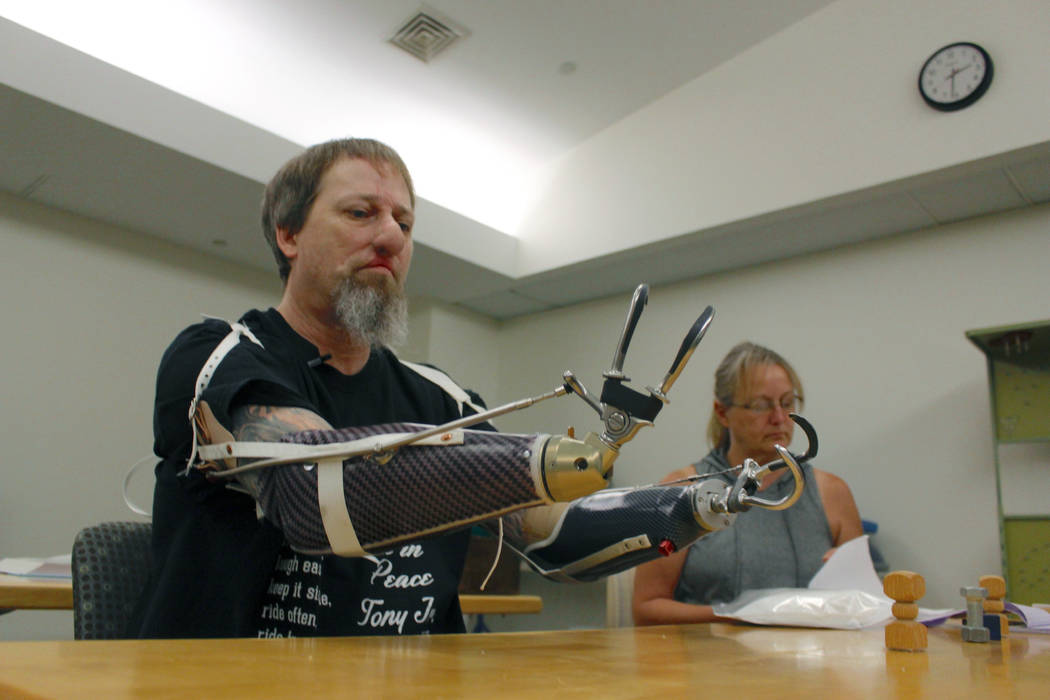 In this Aug. 19, 2019, photo, Greg Manteufel tries out a new prosthetic arm during occupational ...