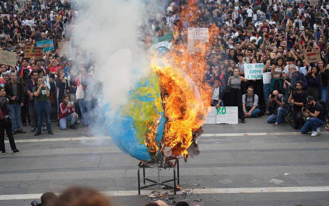 Students set fire to a replica of the planet Earth during a worldwide protest demanding action ...