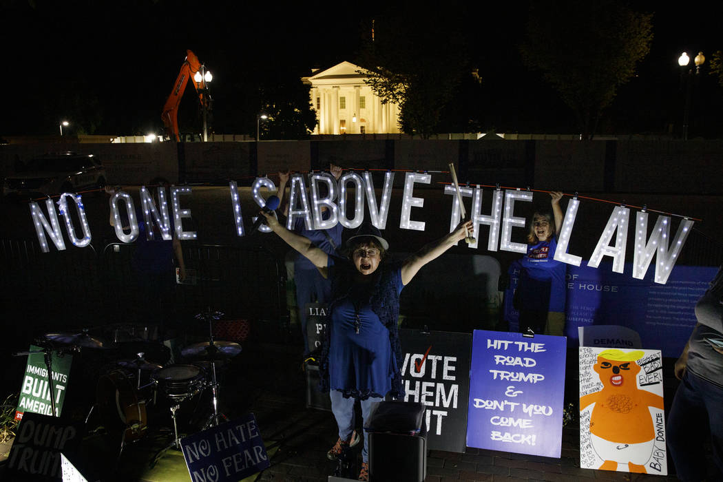 Protesters with Kremlin Annex with a light sign that reads "NO ONE IS ABOVE THE LAW" ...