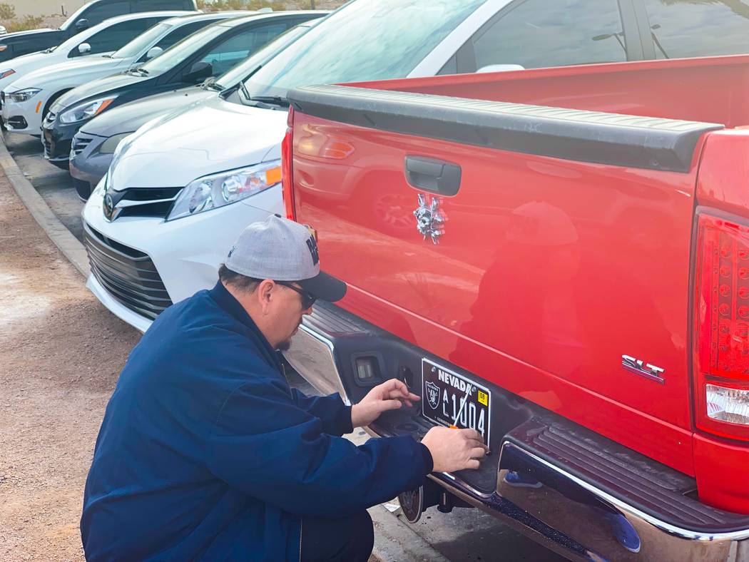 Boulder City resident Tony Cloud attaches his newly acquired Raiders Nevada specialty license p ...