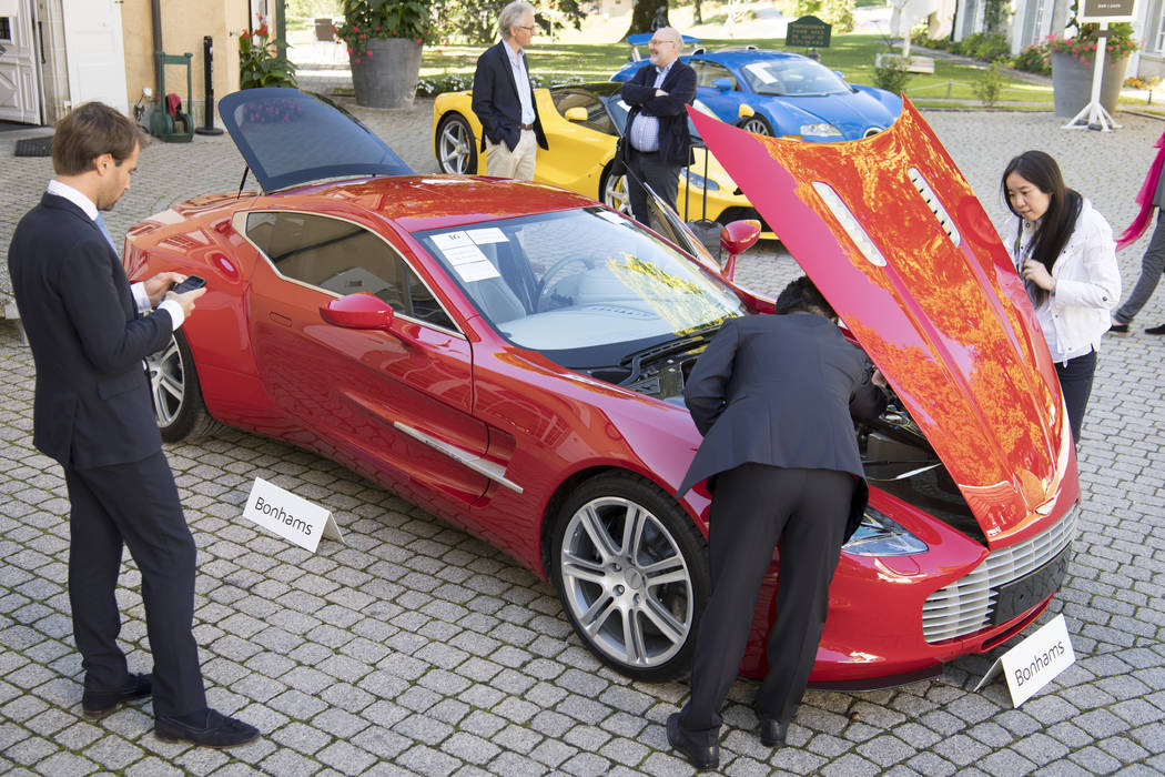 People looking at a Aston Martin One-77 Coupe (2011) in front of a Ferrari LaFerrari (2015), ye ...