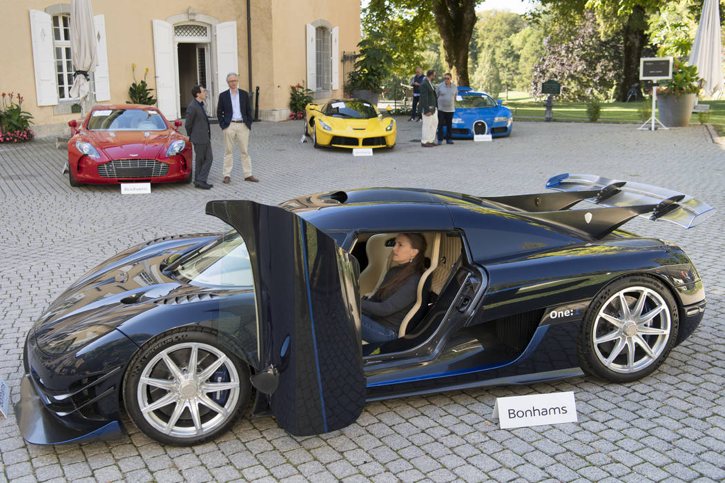 People looking at a 2015 Koenigsegg One:1 model car in front of a Aston Martin One-77 Coupe (20 ...