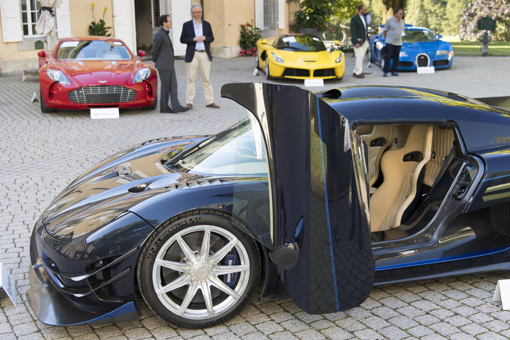 People looking at a 2015 Koenigsegg One:1 model car in front of a Aston Martin One-77 Coupe (20 ...