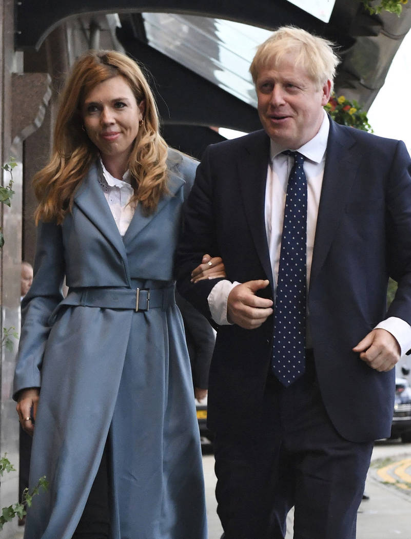 Britain's Prime Minister Boris Johnson arrives, accompanied by partner Carrie Symonds, ahead of ...