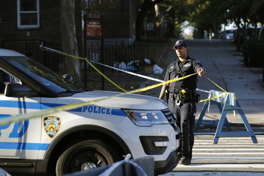 Emergency personnel work near the scene of a fatal shooting of a police officer in the Bronx bo ...