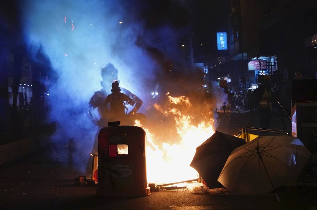 A journalist stands next to fire set by protesters in Hong Kong, Sunday, Sept. 29, 2019. Protes ...