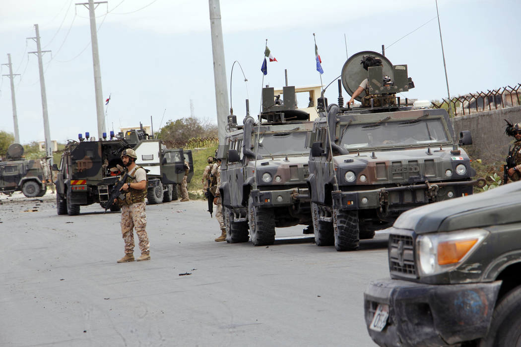 A member of the Italian military stands next to a damaged armored personnel carrier after an at ...