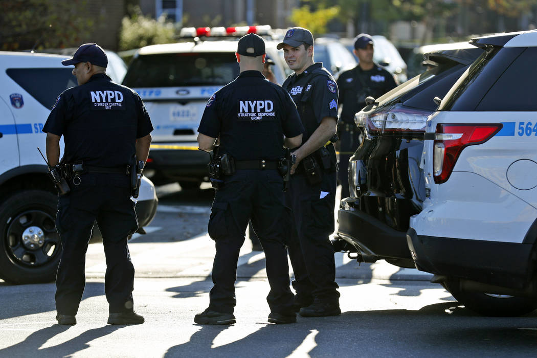 Emergency personnel stand near the scene of a fatal shooting of a police officer in the Bronx b ...