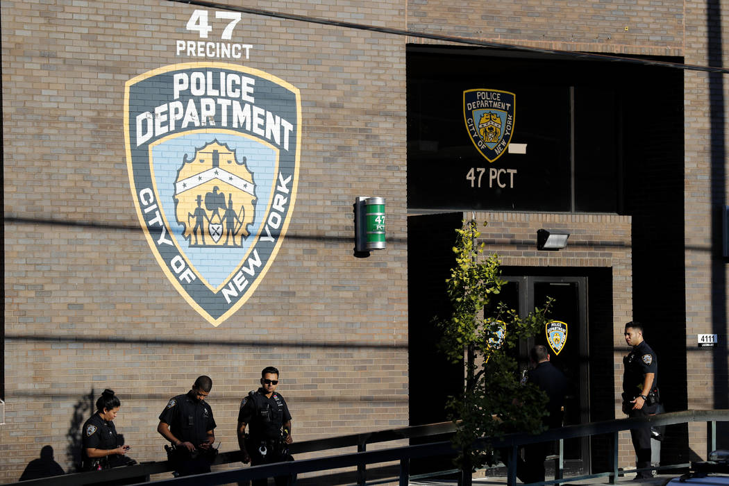 Police officers stand in front of the 47th precinct, near the scene of a fatal shooting of a Ne ...