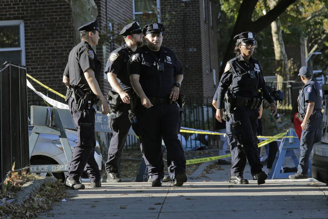 Emergency personnel walk near the scene of a fatal shooting of a New York City police officer i ...
