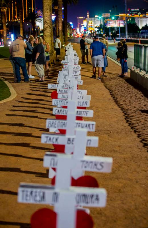 Visitors walk along the line of 58 crosses Greg Zanis placed near the "Welcome to Fabulous Las ...