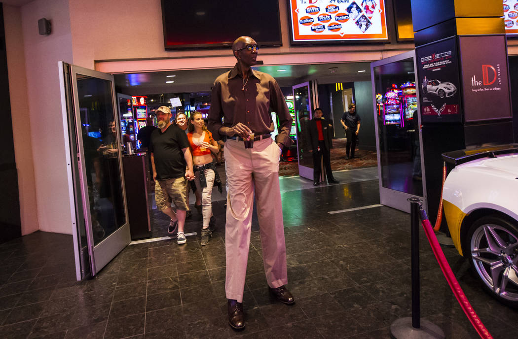 George Bell, who stands 7 feet 8 inches tall, walks outside of The D Las Vegas to the Fremont S ...