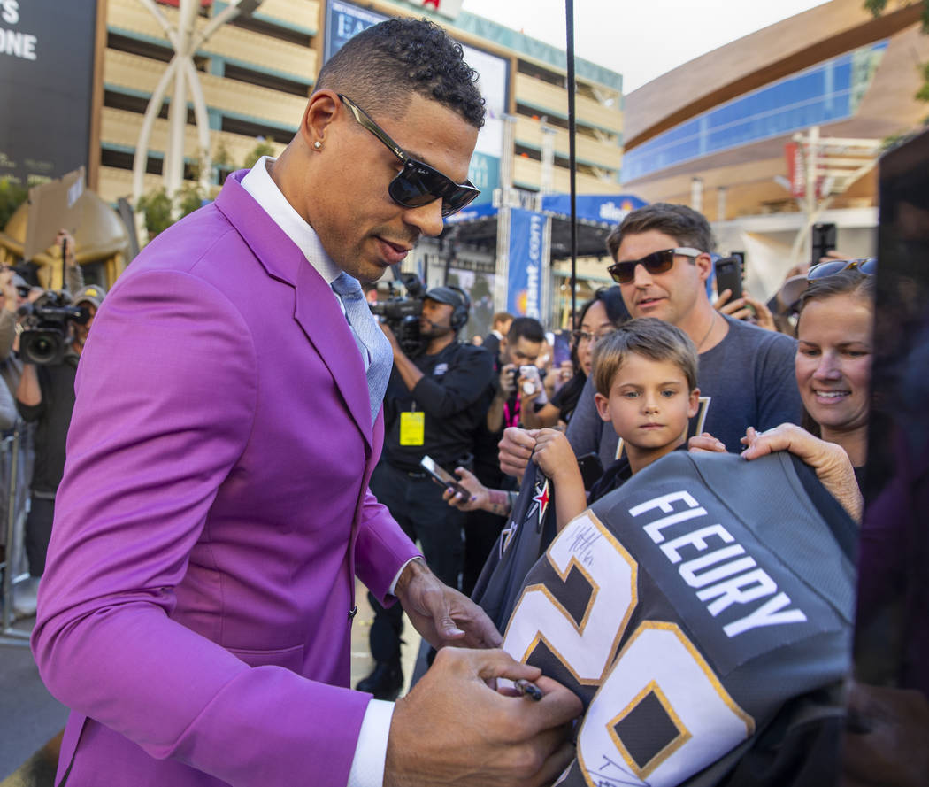 Vegas Golden Knights right wing Ryan Reaves signs an autograph for a fan while walking the gold ...