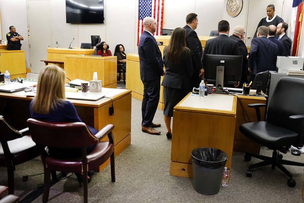 Fired Dallas police officer Amber Guyger, left, sits alone as attorneys from both sides meet wi ...