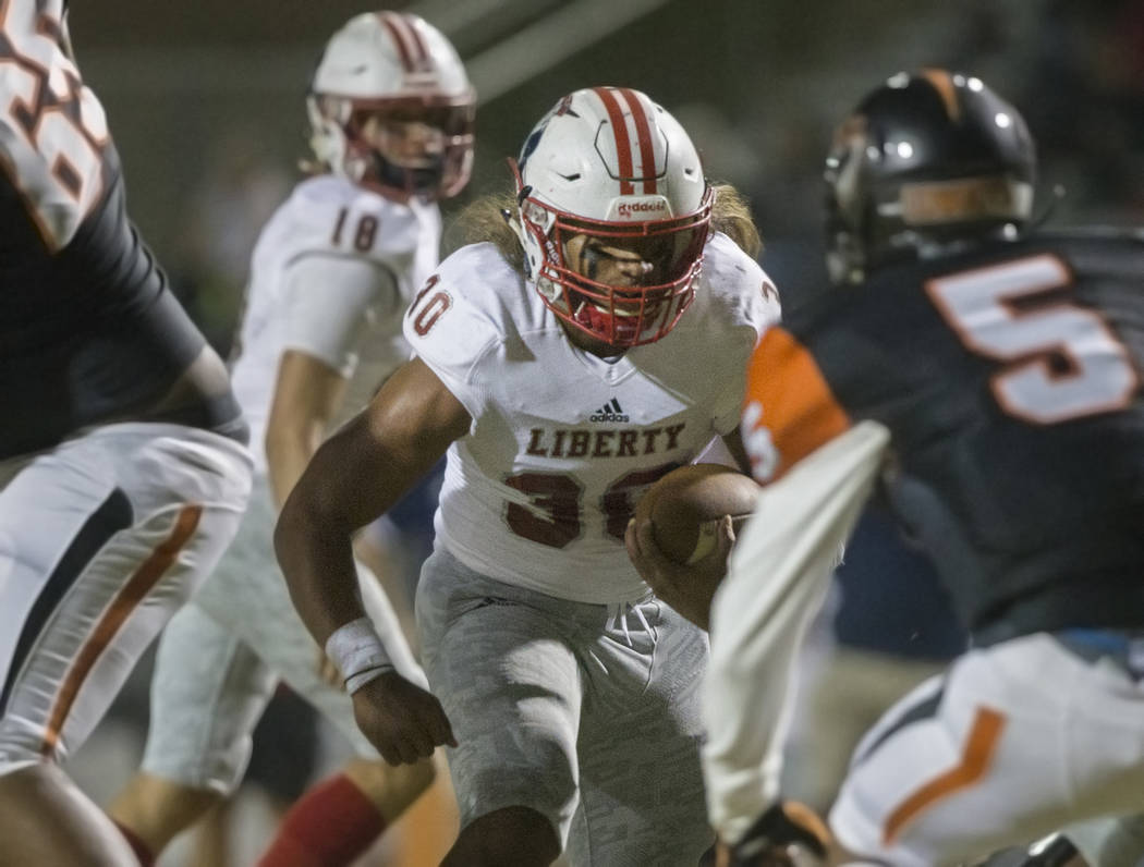 Liberty junior running back Zyrus Fiaseu (30) weaves through traffic past Chaparral senior corn ...