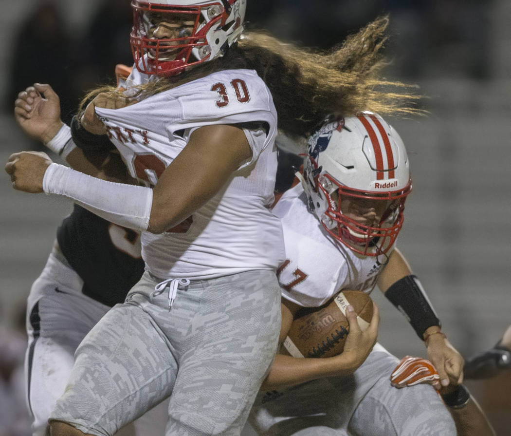 Liberty sophomore quarterback Katin Houser (17) collides with junior running back Zyrus Fiaseu ...