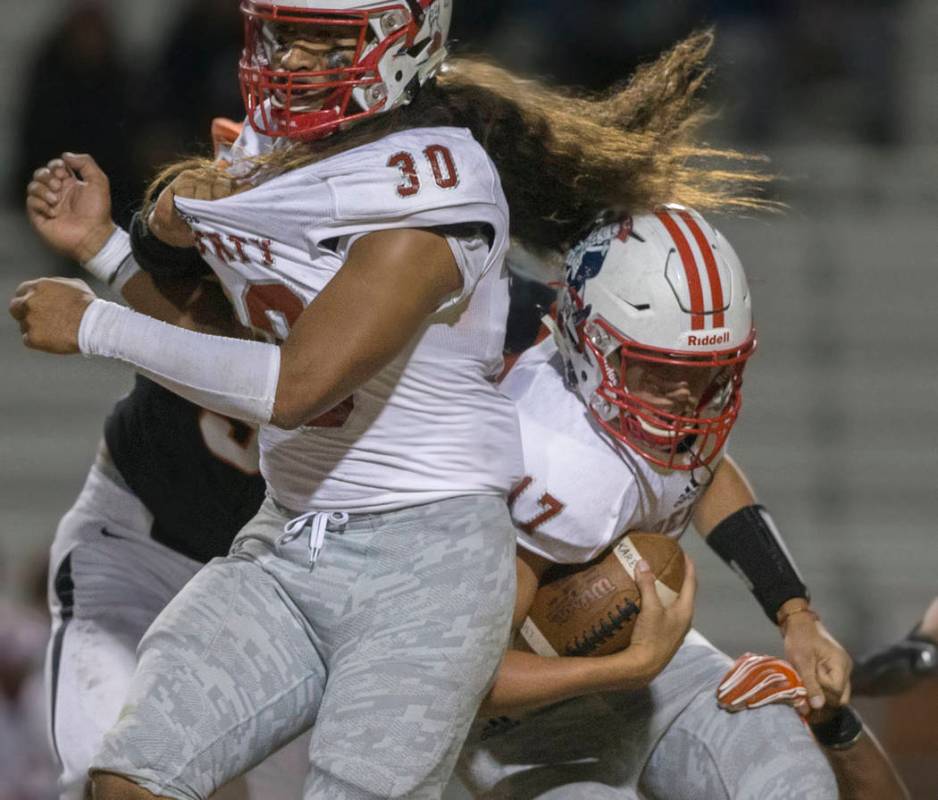 Liberty sophomore quarterback Katin Houser (17) collides with junior running back Zyrus Fiaseu ...