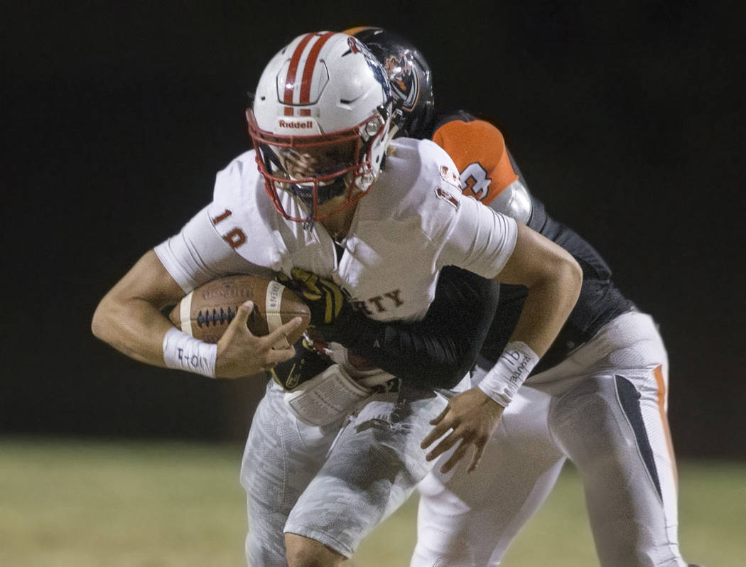 Liberty junior quarterback Daniel Britt (18) tries to break free from Chaparral senior lineback ...