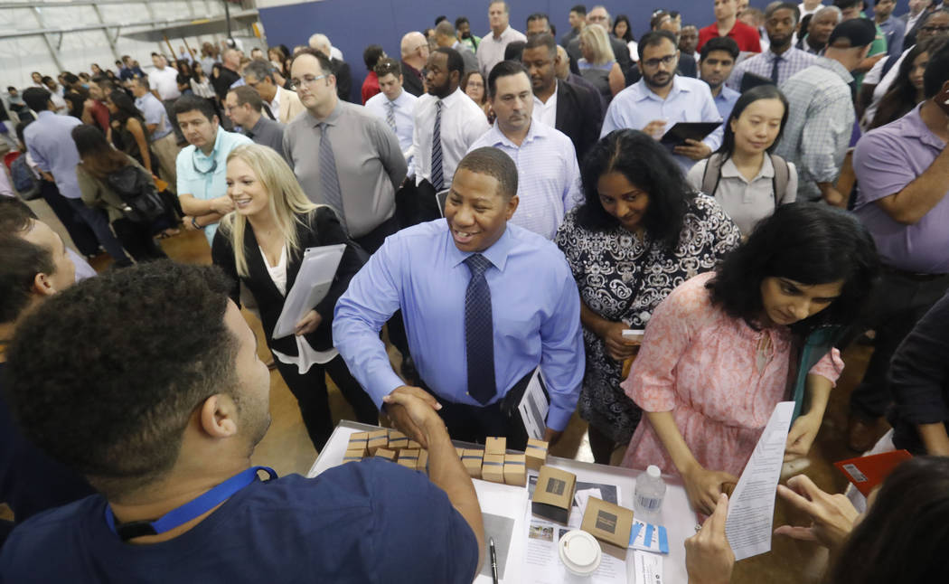 FILE - In this Sept. 17, 2019, file photo job seeker Cedric Edwards, center, shakes hands with ...