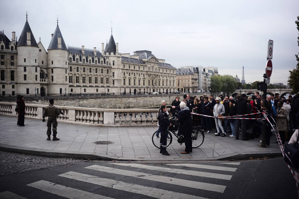 People stand behind a police tape as they are evacuated nearby the police headquarters after an ...