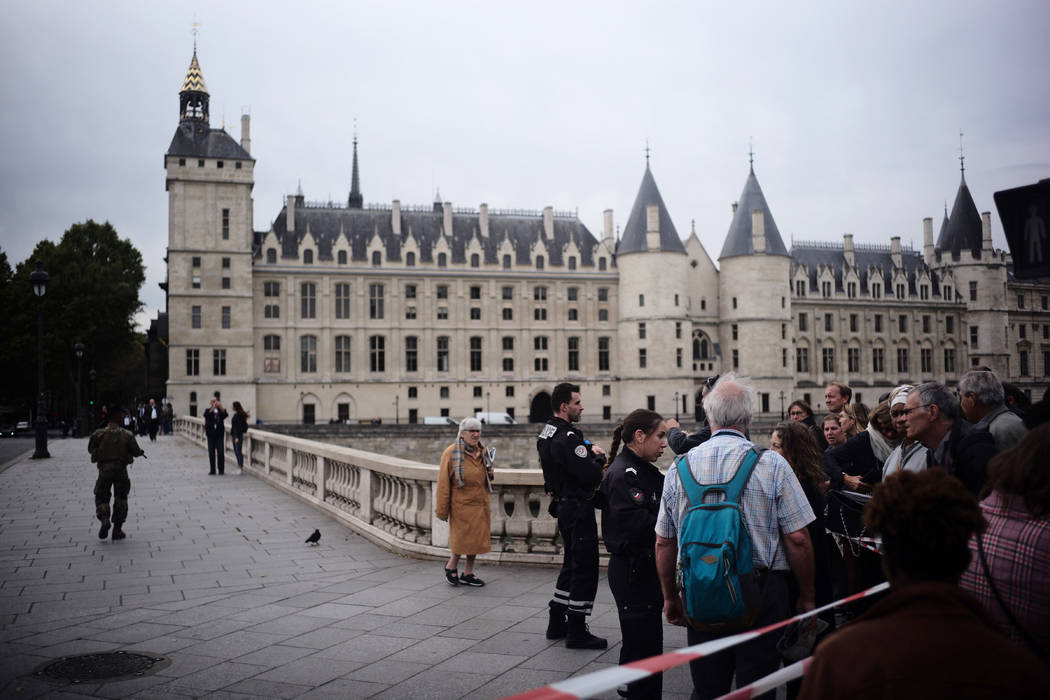 People stand behind a police tape as they are evacuated nearby the police headquarters after an ...