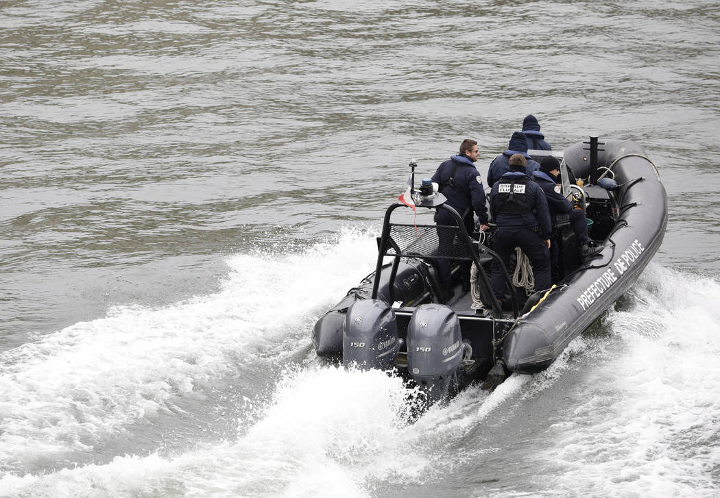 Police officers patrol in a rubber boat on the Seine river after an incident at the police head ...