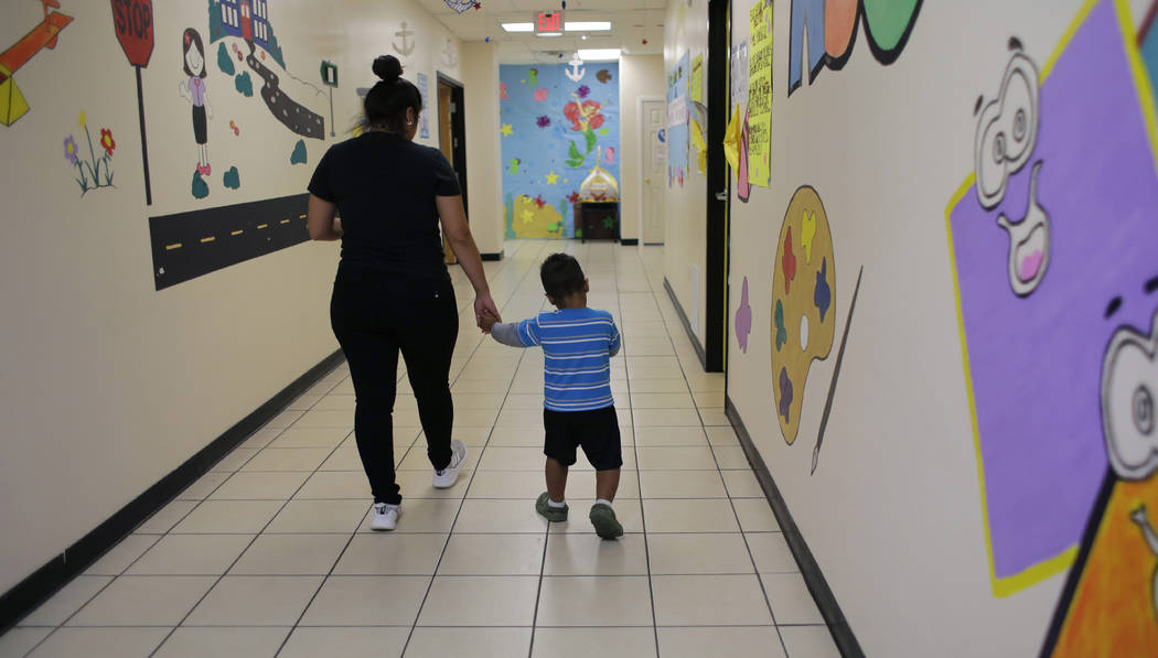 A young migrant boy walks with a Comprehensive Health Services caregiver at a "tender-age& ...