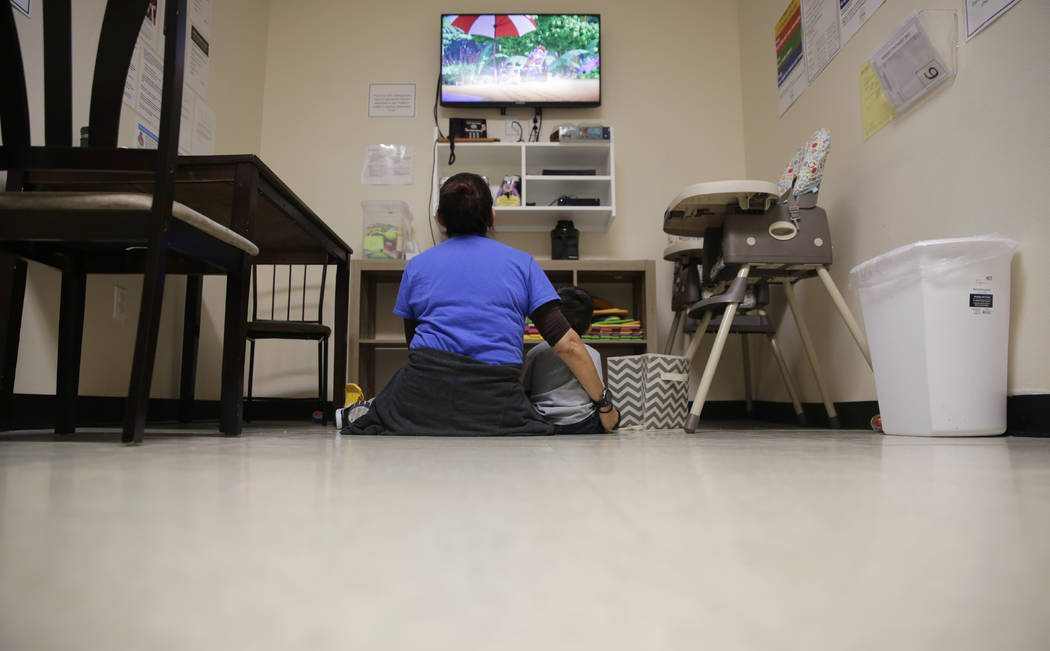 A Comprehensive Health Services caregiver watches TV with a young migrant at a "tender-age ...