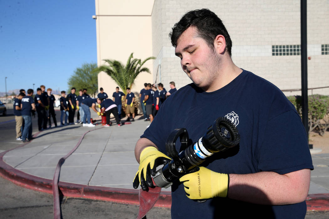 Bonanza High School Fire Science Academy junior Angelo Sanchez attaches a nozzle to a fire hose ...