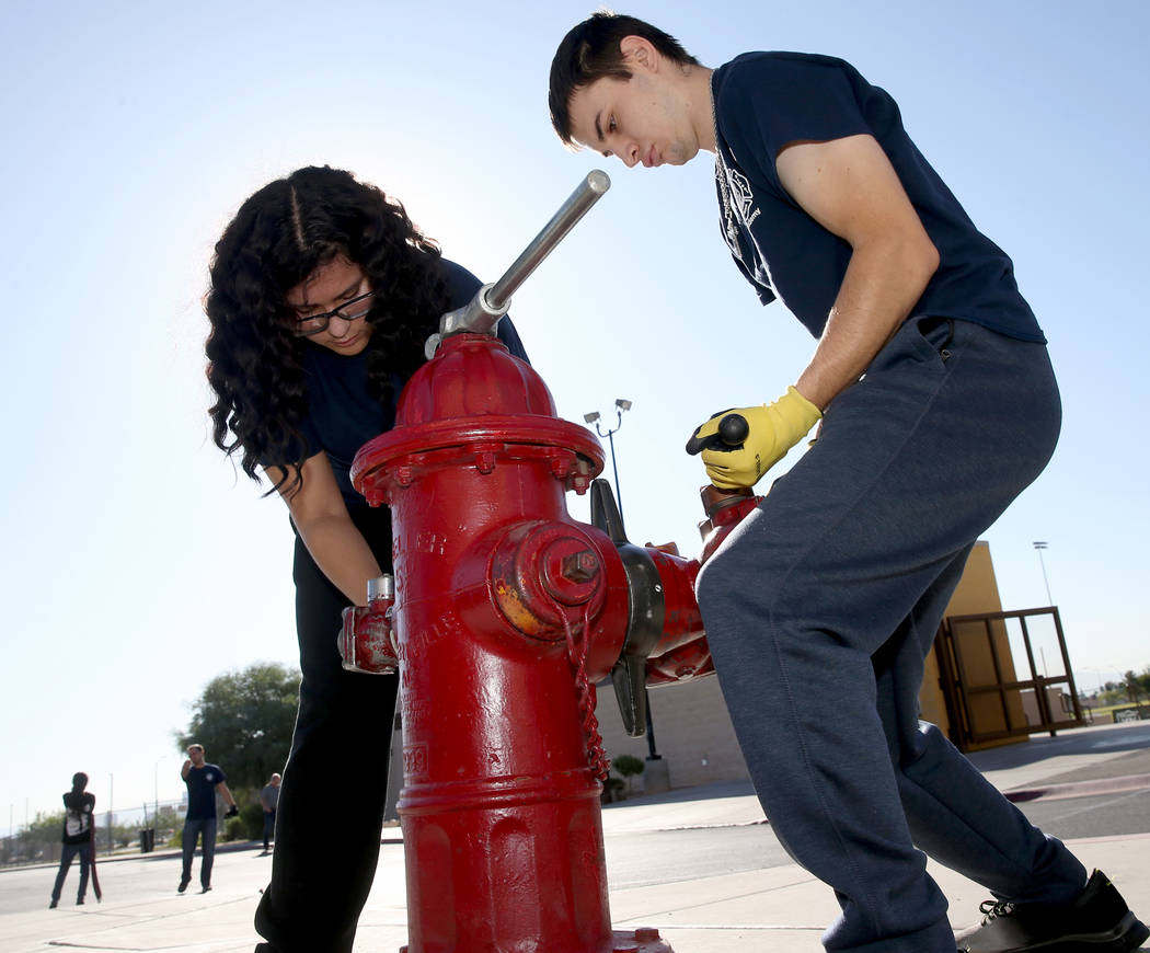Bonanza High School Fire Science Academy student Julie Mendez and Jacob Perez hook a hose up to ...