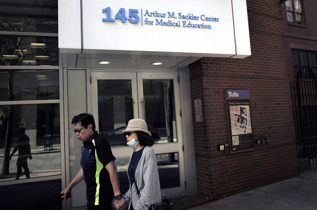 In this Sept. 25, 2019, photo, passers-by walk near an entrance to Tufts School of Medicine in ...