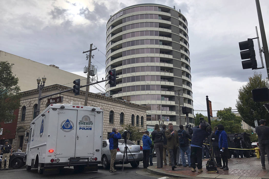 Police respond to a shooting at an apartment building, top rear, in Vancouver, Wash., Thursday, ...