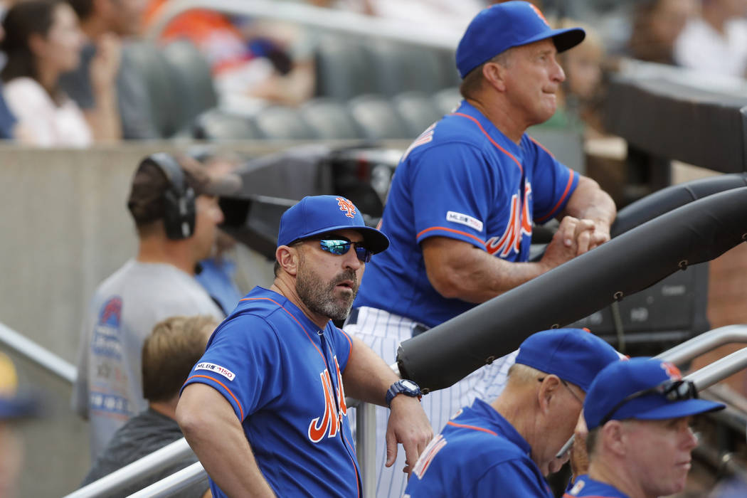 New York Mets manager Mickey Callaway, front left, looks from the dugout during a baseball game ...