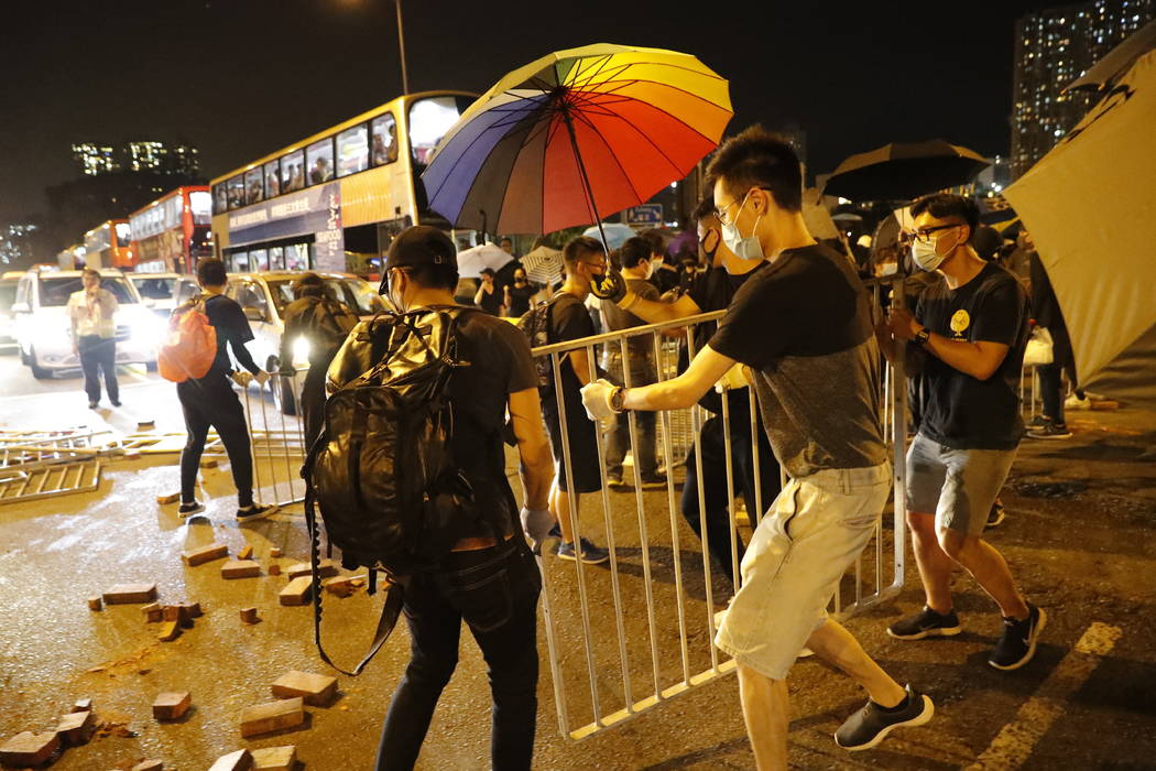 Protesters wear masks and block a street in Hong Kong Friday, Oct. 4, 2019. Thousands of defian ...