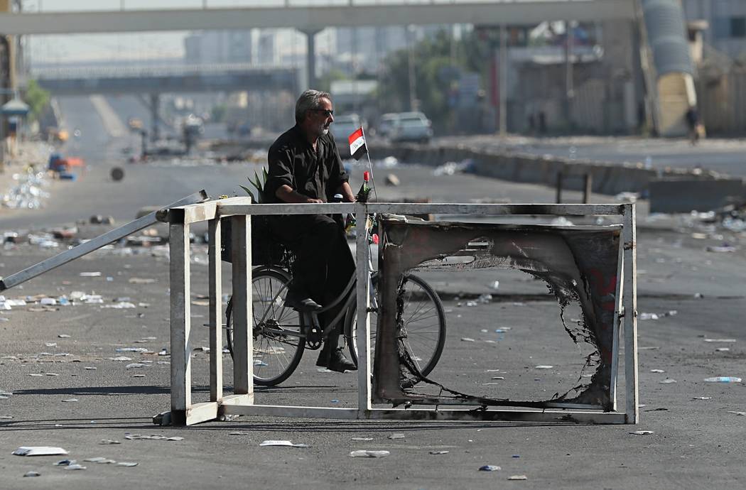 A man rides a bicycle in the protest site area in Baghdad, Iraq, Friday, Oct. 4, 2019. Iraq's p ...