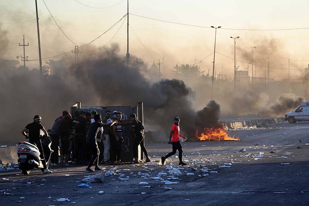 Anti-government protesters set fires and close a street during a demonstration in Baghdad, Iraq ...