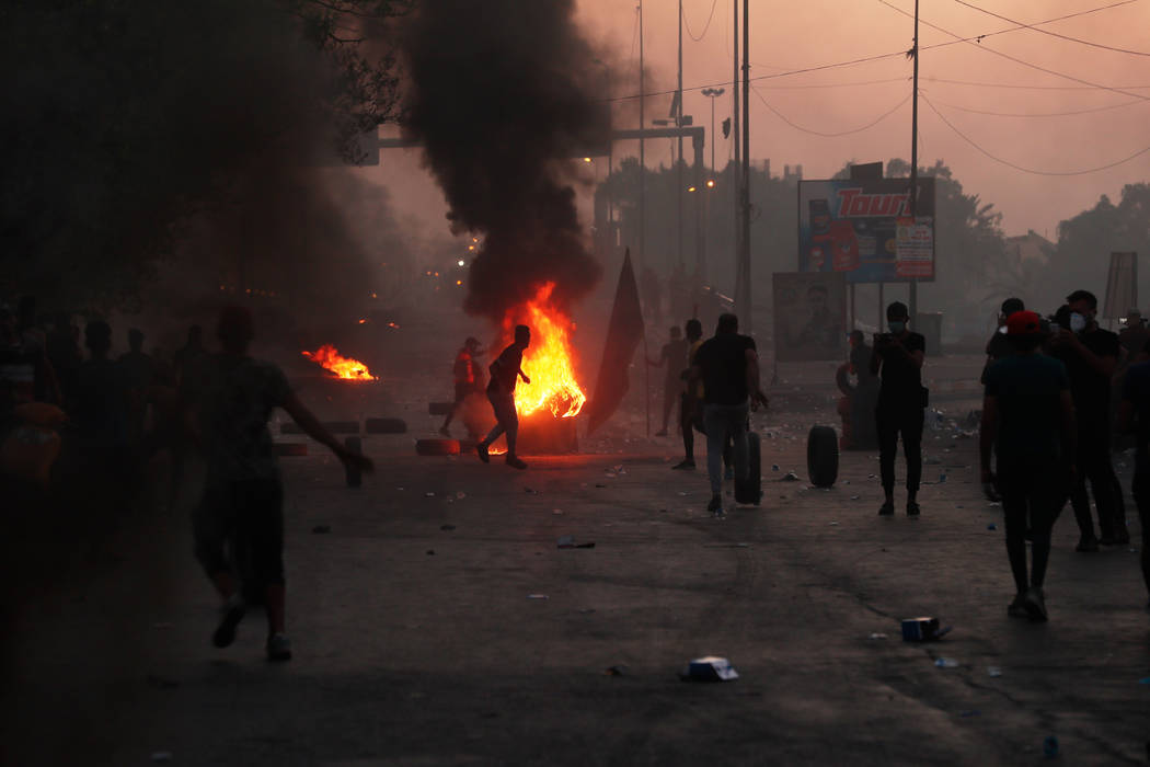 Anti-government protesters set fires and close a street during a demonstration in Baghdad, Iraq ...