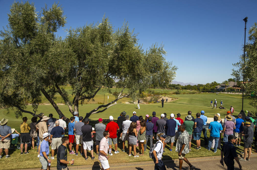 The gallery crowds around as Kevin Na and Patrick Cantlay approach the green at hole 3 during t ...