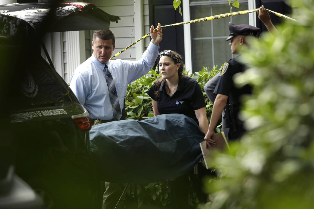 A woman from the Massachusetts Chief Medical Examiners Office, center, uses a gurney to place h ...