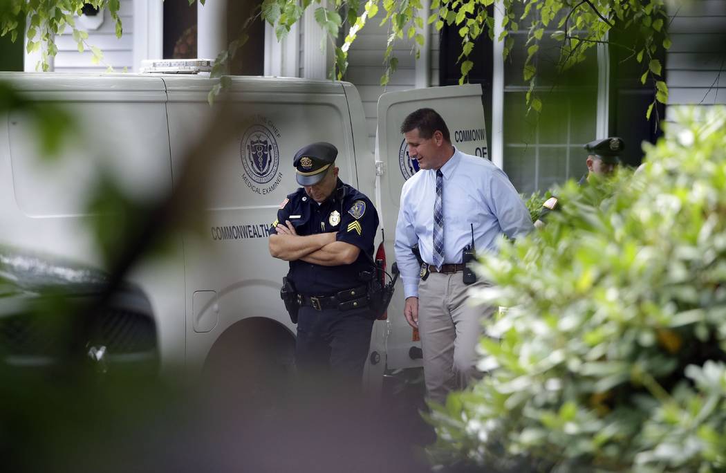 Officials work outside a home where two adults and three children were found dead with gunshot ...