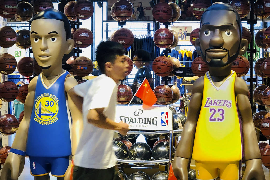 A man walks past statues of NBA players Stephen Curry of the Golden State Warriors, left, and L ...