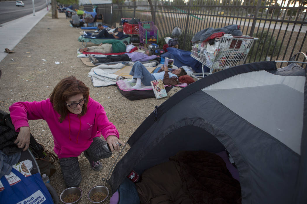 Jody Mathews, who is homeless, feeds her two dogs next to her tent where she stays along Las Ve ...