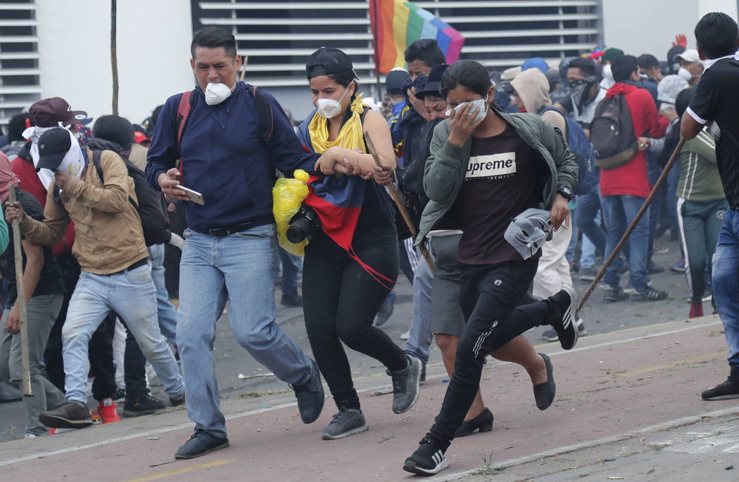 Anti-government protesters run from tear has fired by police near the National Assembly in Quit ...